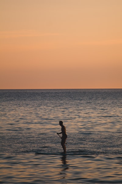 夕阳下走在沙滩上的女人的剪影